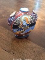 Front view of the Japanese porcelain snuff bottle showing detailed raised design of a traditional figure with gold, blue, and orange colors.