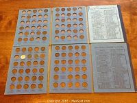 Complete view of blue coin boards with circular slots for pennies, some coins present, including two reference papers