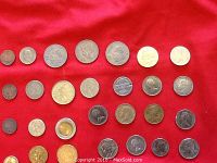 Coins laid out on red fabric showing multiple US coins including Indian Head Pennies and other foreign coins.