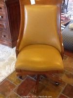 Front view of a leather and wood office chair with caster wheels, showing the seat and backrest upholstery.