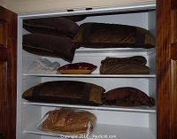 Shelved view showing brown and gold European pillows and king size pillows, folded sheets, and a pillow with a red and gold diamond pattern.