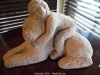 Photo of a sculpture showing a child reclining on a large dog with detailed fur texture, soft matte finish, and peaceful expression.