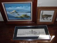 Four signed wall art pieces displayed including seascape with wooden frame, kitten drawing in brown frame, and Pittsburgh skyline pencil sketch under glass.