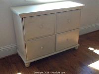 Front view of the wooden four drawer filing cabinet showing flat top, four drawers with round knob handles, and short feet.