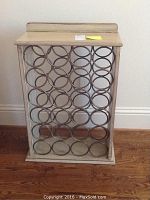 Front view of wine rack showing circular metal holders for bottles inside wooden frame.