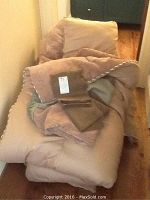 Queen-sized folded beige comforter with pillow shams, showing fabric tags.