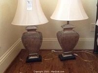 Two matching crocodile pattern textured table lamps with white fabric shades on a hardwood floor near a wall.