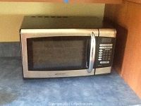 Emerson microwave on a counter showing front view with closed door and control panel.
