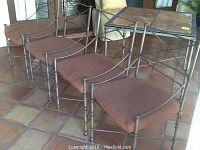 Photo of four iron chairs lined up with brown cushions on a tiled floor showing the front seating area.
