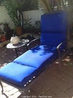Blue cushioned outdoor chaise lounge under shaded patio area.