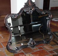 Full view of the ornate wood framed mirror showing the intricate carved wood frame and reflective surface.