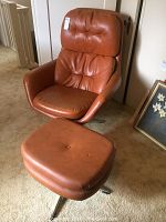 Front view of cognac leather swivel lounge chair with ottoman on carpet