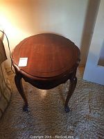 Top-down view of a round wooden side table showing scalloped edges and polished finish.