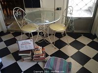 Full view of the cafe table set with two chairs and stack of cookbooks on floor beside the table