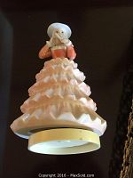Porcelain musical lady figurine in peach ruffled dress, about 7 inches tall, viewed from below showing base
