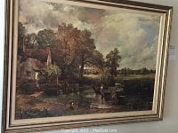 Framed art print of countryside scene with pond, trees, rustic home, and figures with a cart