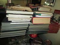 Stack of multiple books, some hardcovers and paperbacks, showing worn condition and varied thickness.