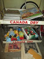 Metal Canada Dry cart holding stacks of vintage life magazines, Flintstones cards, Simpsons dolls, and boxed Lego set
