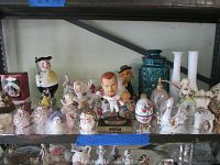 Overall view of multiple figurines arranged on a shelf, including a bobblehead, Disney figurines, swan, vase, and other figurines.