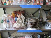 Metal shelf holding assorted collectibles including beer mugs, dog figurine, porcelain figurines and several stacks of plates
