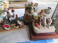 Photo of three Norman Rockwell figurines with music box bases and other small figurines on a table