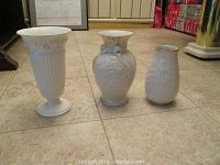 Three vases: two white Lenox vases with embossed floral patterns and one Wedgewood vase, showing shapes and details from angle