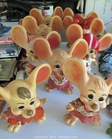 Nine plastic Topo Gigio figurines arranged together showing various outfits and large ears.