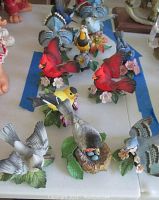 Wide view of multiple Lenox bird figurines including cardinals, blue jays, and others on a white surface