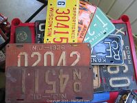 Pile of vintage license plates with visible New Jersey 1926 and 1931 plates, Wisconsin, Aruba, and others.