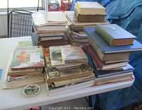 Photo showing stacks of vintage books and magazines piled on a table with visible wear and signs of age.