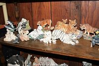 Wooden shelf displaying various animal figurines with tigers, bobcats, pandas, and other animals visible.