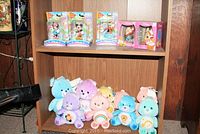 Seven Care Bears plush toys arranged on a bottom shelf of a wood shelf unit