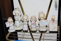Five Precious Moments figurines and one Enesco Bridesmaid figurine displayed on metal racks