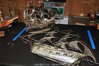 Two metal ship models on a table showing their size and condition, with visible wear and dust.