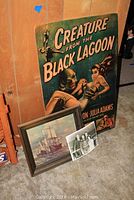 Mounted Creature from the Black Lagoon poster positioned upright, ship print and photo resting on floor in front