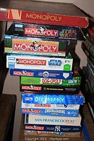 Stack of various Monopoly game boxes showing themes including Star Wars, NHL, New York Yankees, San Francisco, Dog-opoly, Oceanopoly, Cheerleading, and classic editions