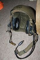 Vietnam era helmet showing front with padded ear cups and chin strap, olive drab color with number '60' on top.