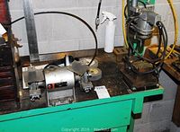 Bench with Ashland grinder and drill press side by side with shop tools around