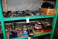 Shelves filled with assorted mechanical parts including belts, screws, parts in containers, and cardboard box