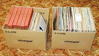 Two cardboard boxes labeled “vinegar” each containing stacks of vinyl LP records
