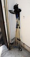 Photo showing three pairs of poles leaning against a wall: two sets of walking poles, one set of ski poles.