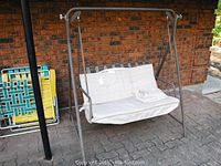 Front view of metal frame porch swing with cushioned seat and folded cover.