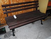 Front view of park bench showing wooden slats and cast iron legs on concrete floor