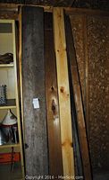 Full view of various wooden boards leaning against a wall with mixed widths and colors.