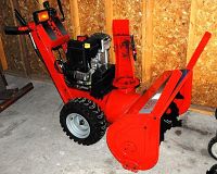 Left-side perspective showing red steel housing, black engine and large treaded tires