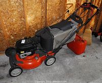Overall left-side view of mower showing deck, engine housing, grass catcher bag and red gas can at rear
