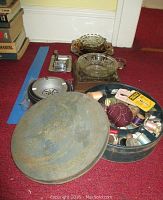 Overall lot including metal tin, various glass ashtrays, and sewing items on red carpet
