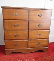 Front view of wood dresser showing 8 drawers with brass handles and medium brown finish.