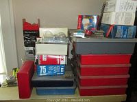 View of stacked tool kits and boxes containing various home repair supplies including light bulbs and nails.