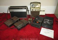 View of the six vintage electronics on red carpet, showing the Realistic CTR-73 tape recorder, Sergeant AM/FM radio, GE 7-4612A clock radio, Magnavox D3150/17 clock radio, Sony TC-8 8-track recorder, and two wireless microphones.
